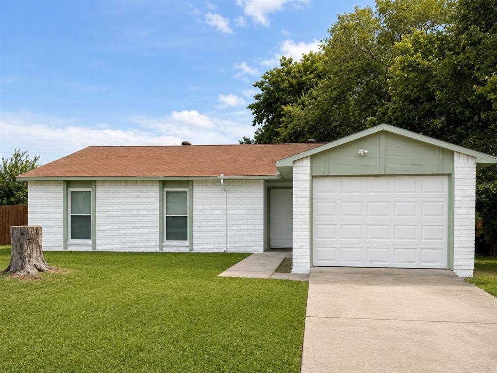 542 Hanover Drive, Allen, TX 75002 White brick exterior with a brown shingle roof, featuring a single-car garage with a panel door, a paved driveway, and a concrete walkway