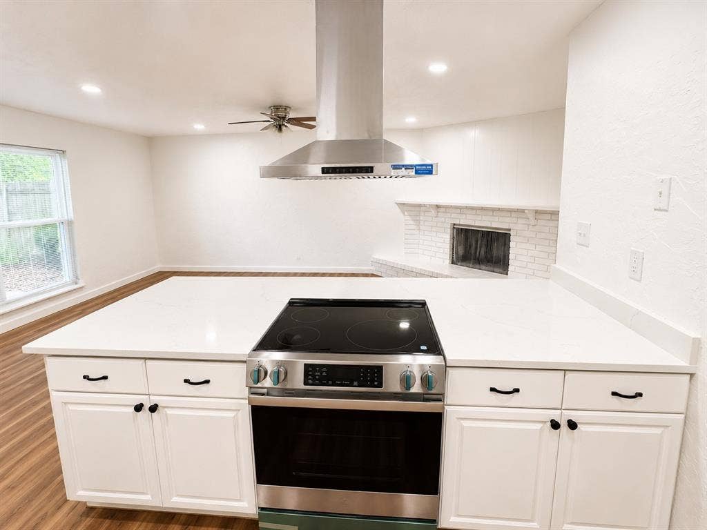 542 Hanover Drive, Allen, TX 75002 Spacious kitchen island featuring a built-in range, bright white cabinetry, and a sleek stainless steel range hood