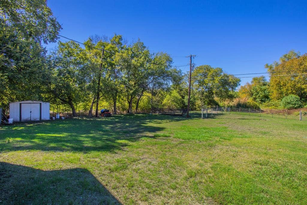 Expansive grass lawn with mature trees and a dedicated storage shed