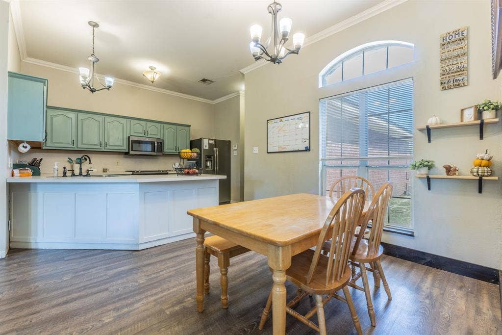 Open-concept kitchen and dining area featuring a kitchen island with paneling, wood-finish flooring, and a large window with an arched transom