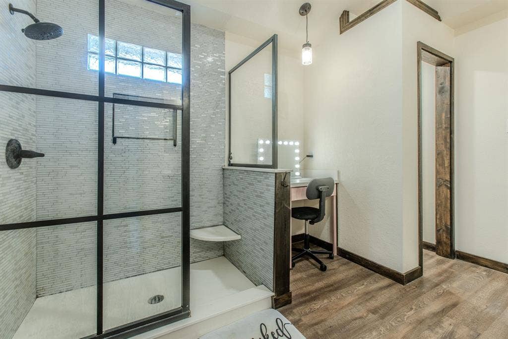 Walk-in shower with dark-framed glass enclosure, built-in corner bench, and mosaic tile surround