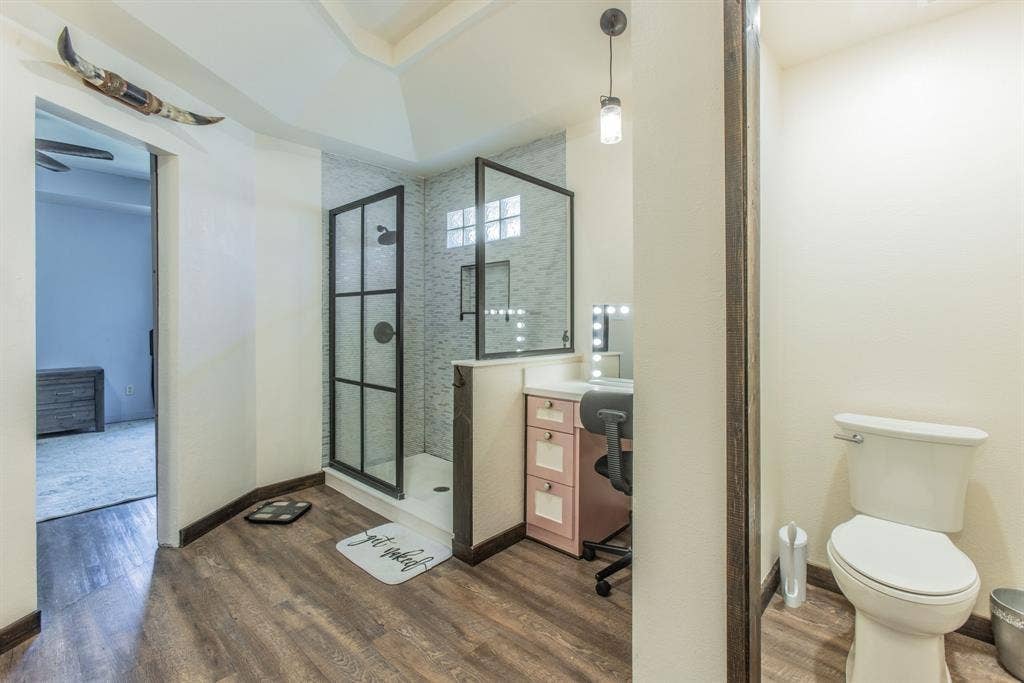 Walk-in shower with black-framed glass enclosure, tiled accent wall, and built-in vanity with cabinetry