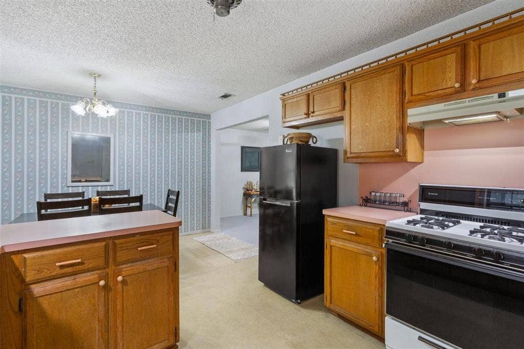 204 Ausborn Street, Eddy, TX 76524 Kitchen with wood-finish cabinetry, a gas range, and a full-size black refrigerator