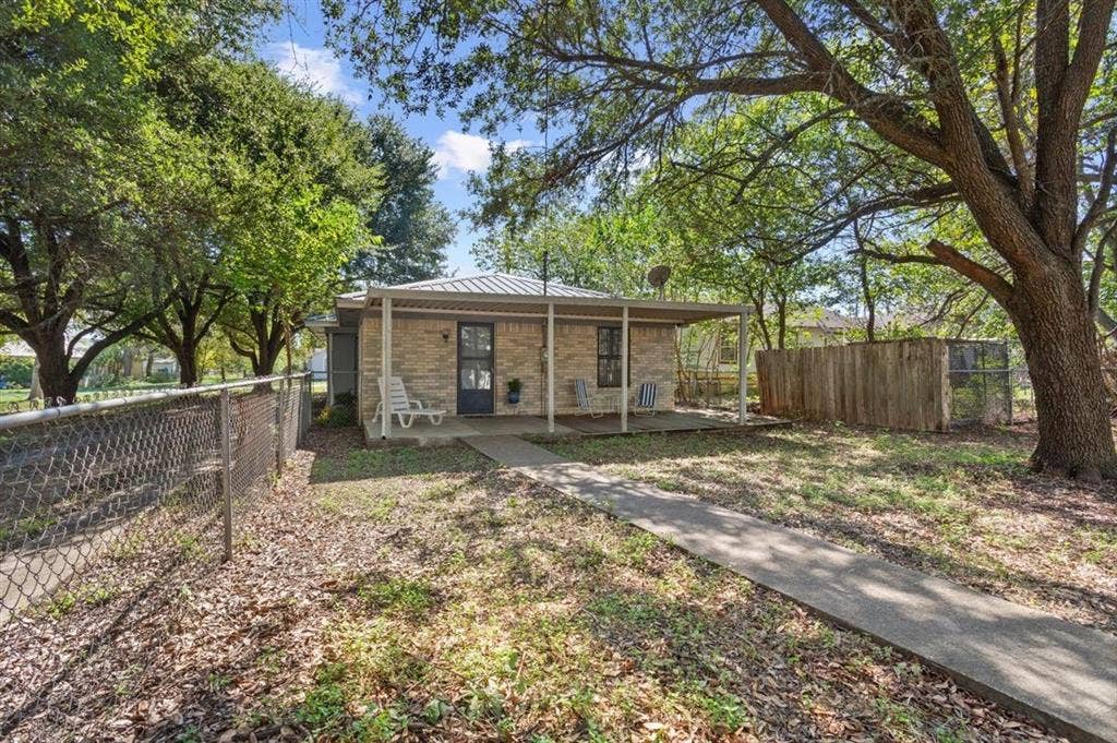 204 Ausborn Street, Eddy, TX 76524 Brick exterior with covered front porch, a paved walkway, and mature trees
