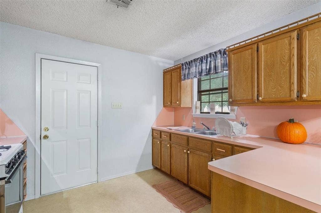 204 Ausborn Street, Eddy, TX 76524 Kitchen featuring wood-finish cabinetry, a double basin sink, and a built-in oven with a stovetop