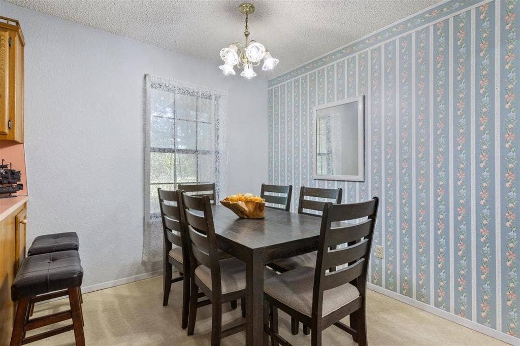 204 Ausborn Street, Eddy, TX 76524 Dining area with a window, decorative wallpaper, and a ceiling-mounted light fixture