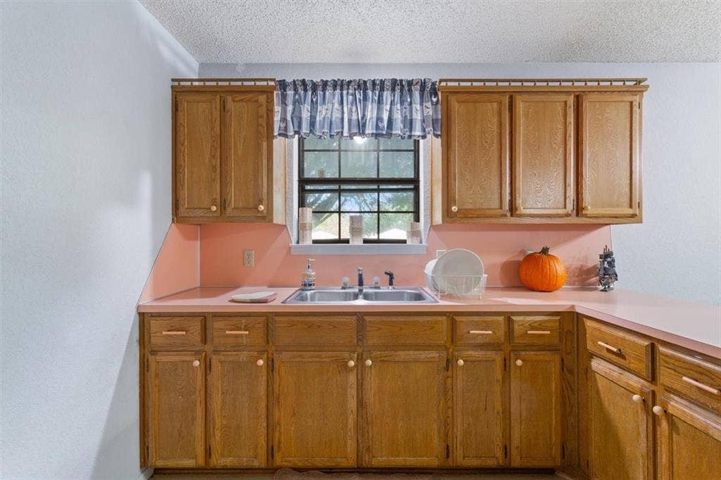 204 Ausborn Street, Eddy, TX 76524 Kitchen featuring wood cabinets, a double basin sink, and ample countertop space