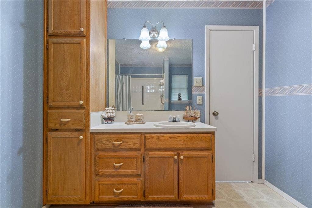 204 Ausborn Street, Eddy, TX 76524 Wood-finish vanity with a white countertop and an integrated sink