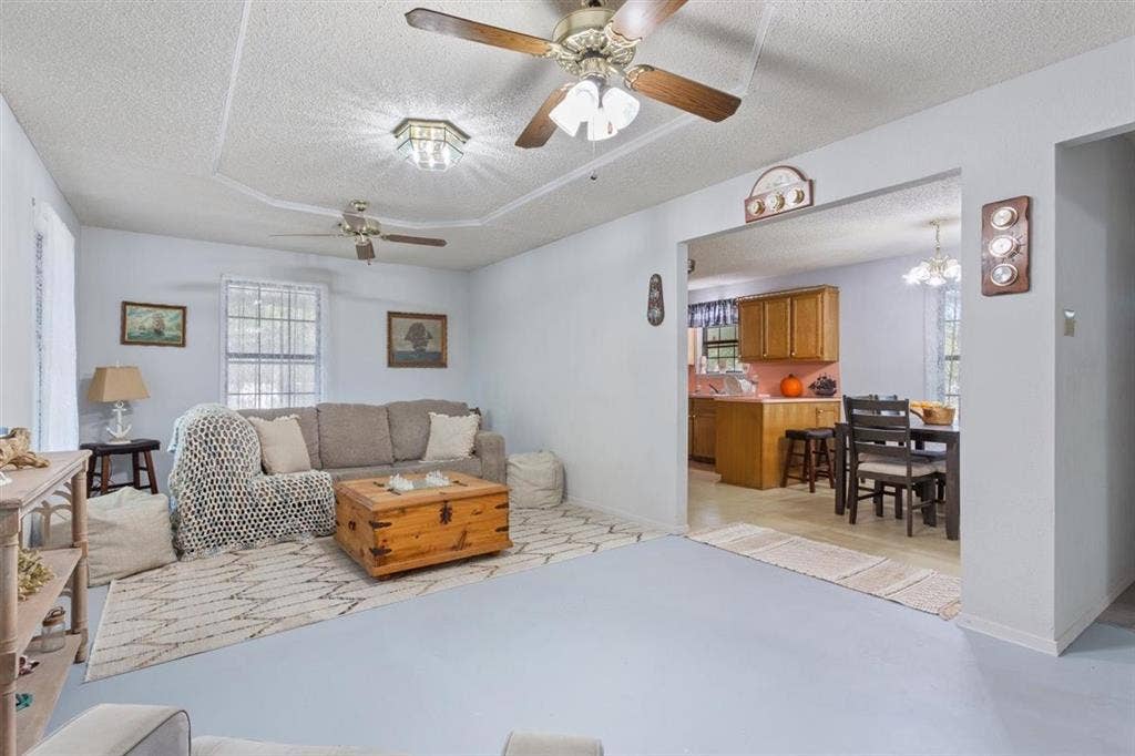 204 Ausborn Street, Eddy, TX 76524 Tray ceiling with decorative trim, multiple ceiling fans, recessed lighting fixture, arched entryway, and wood-finish cabinetry