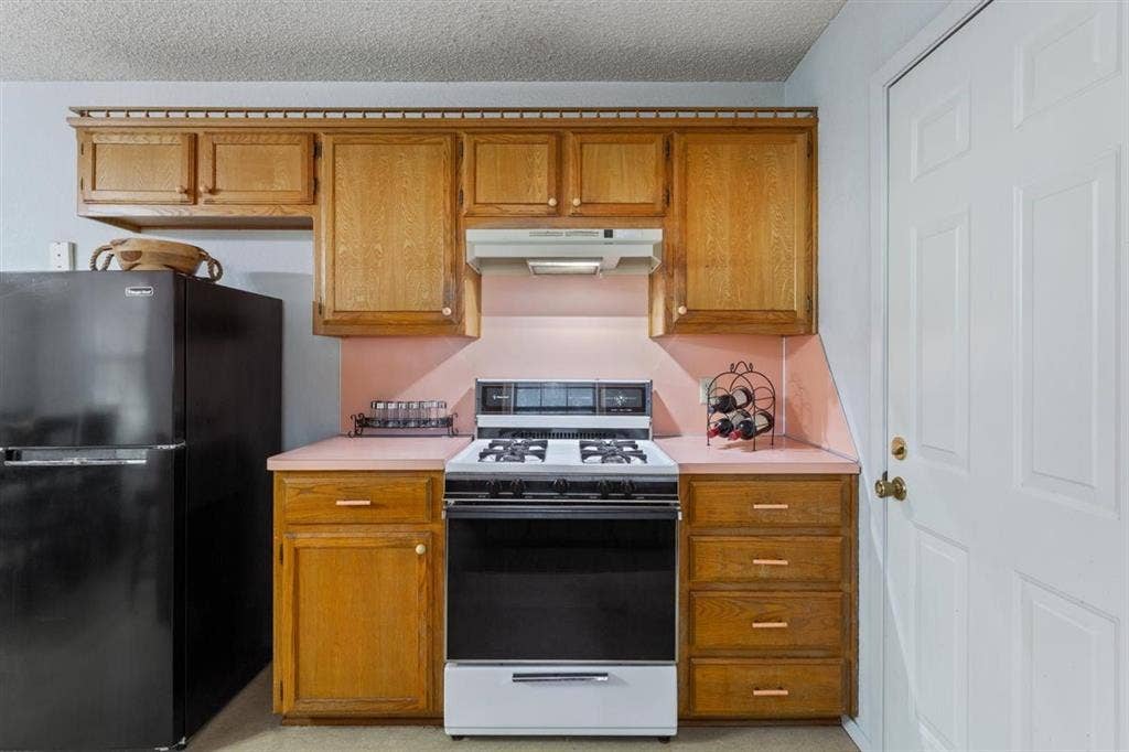 204 Ausborn Street, Eddy, TX 76524 Kitchen featuring wood cabinetry, a gas range, an exhaust hood, and a paneled door