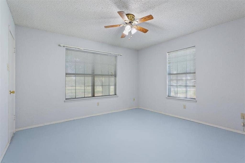 204 Ausborn Street, Eddy, TX 76524 Wood-blade ceiling fan with integrated lighting, two windows with blinds, and light blue flooring