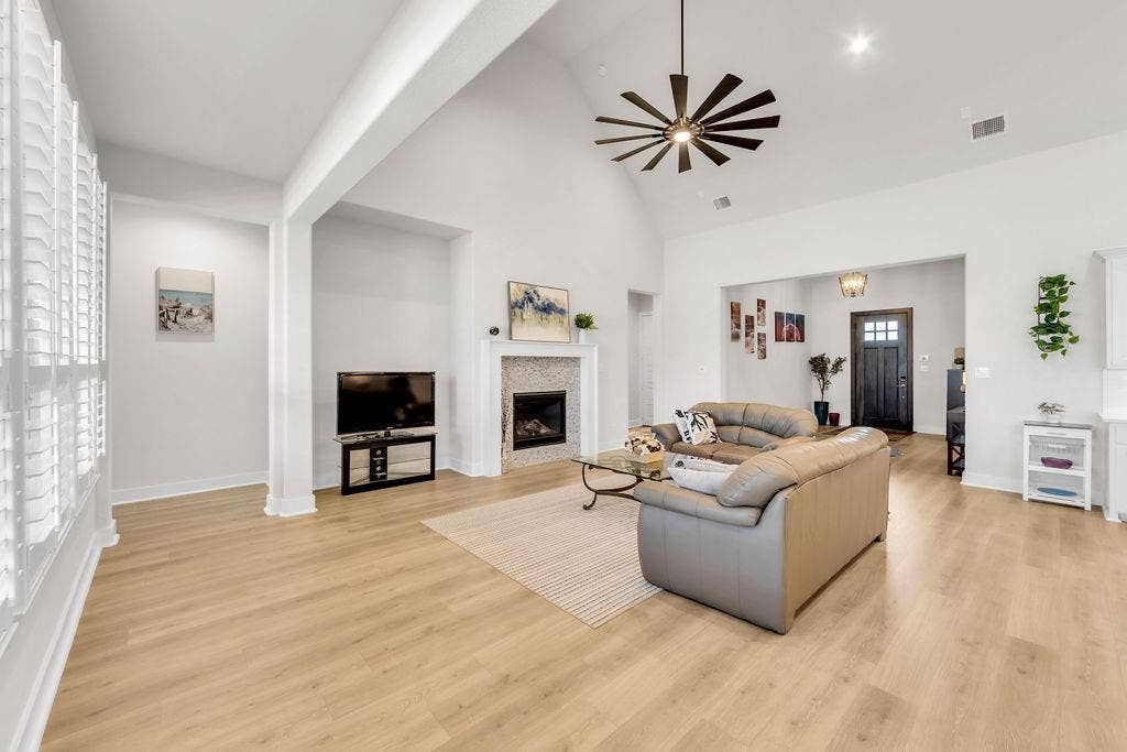 2971 Gaulding Drive, Prosper, TX 75078 Vaulted ceiling with a contemporary ceiling fan, wood-finish flooring, and a fireplace with a decorative tile surround