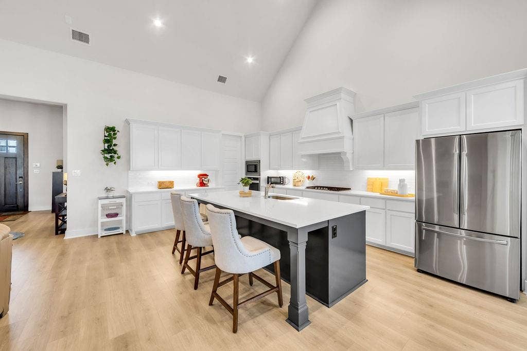 2971 Gaulding Drive, Prosper, TX 75078 High vaulted ceiling, wood-finish flooring, white cabinetry with crown molding, stainless steel French door refrigerator, and a kitchen island with seating