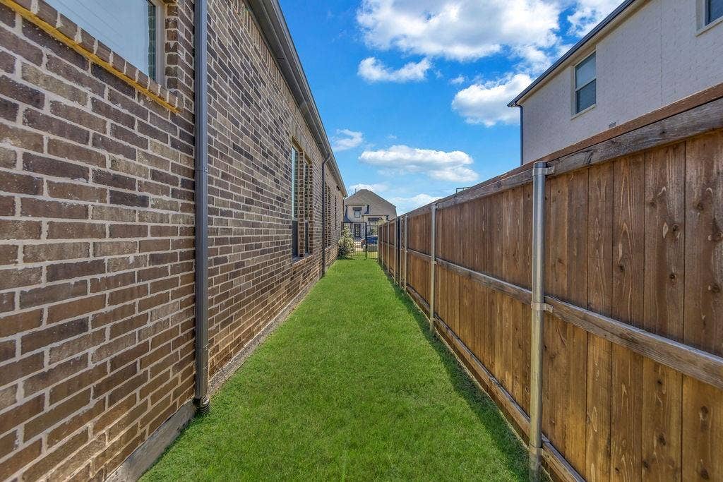 2971 Gaulding Drive, Prosper, TX 75078 Manicured lawn area featuring a brick exterior, functional gutters, and a wood privacy fence