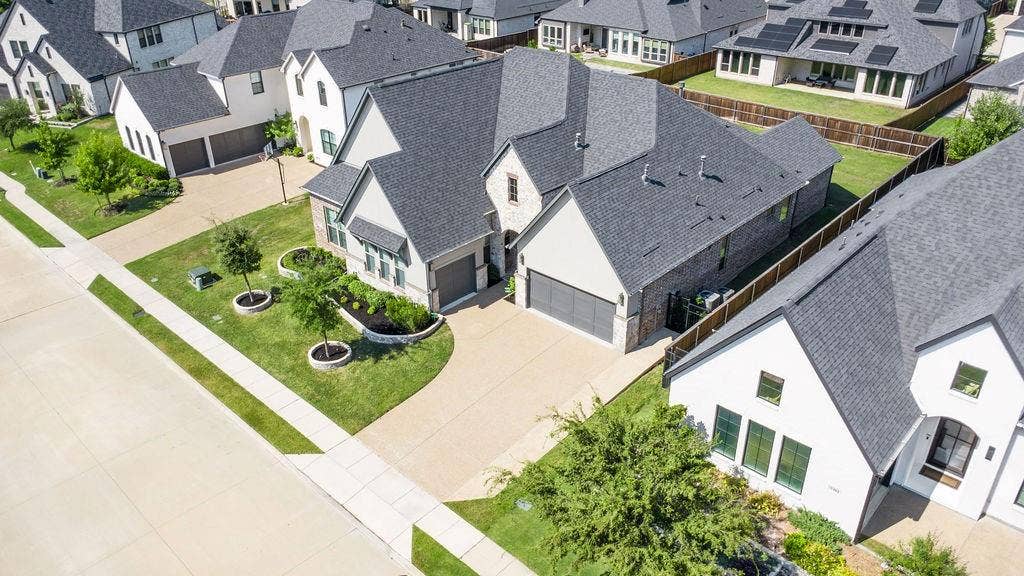 2971 Gaulding Drive, Prosper, TX 75078 Two-story residence featuring a dark gray shingle roof, brick and light-colored siding exterior, and an attached two-car garage
