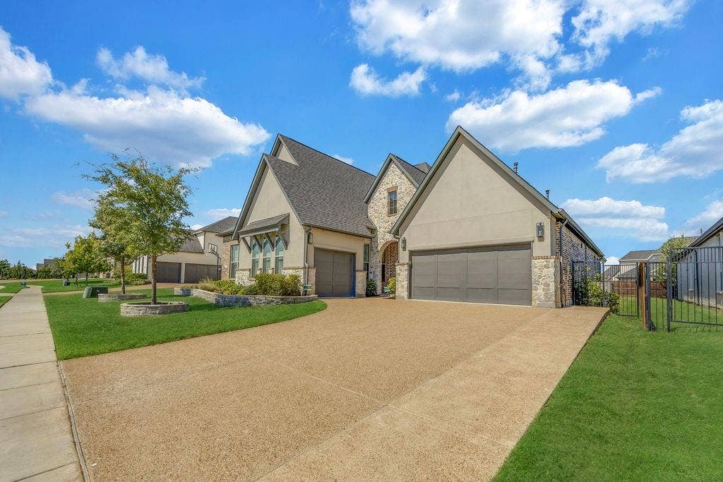 2971 Gaulding Drive, Prosper, TX 75078 Stucco and stone exterior, gabled roofline, two integrated garages, concrete driveway, and a wrought iron fence