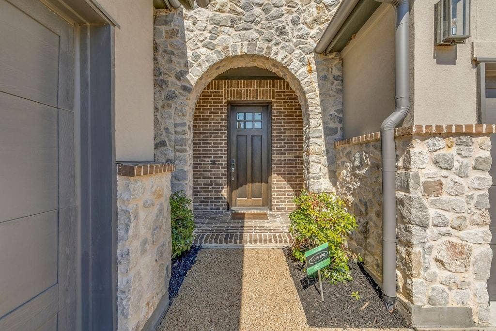 2971 Gaulding Drive, Prosper, TX 75078 Stone and brick exterior with an arched entryway, leading to a dark wood-paneled door