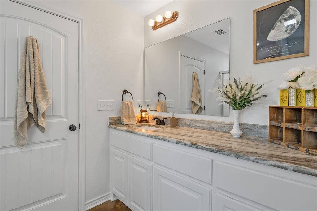 19731 County Road 4130, Lindale, TX 75771 White painted wood cabinetry with brushed nickel hardware, a rectangular undermount sink, and a stone countertop
