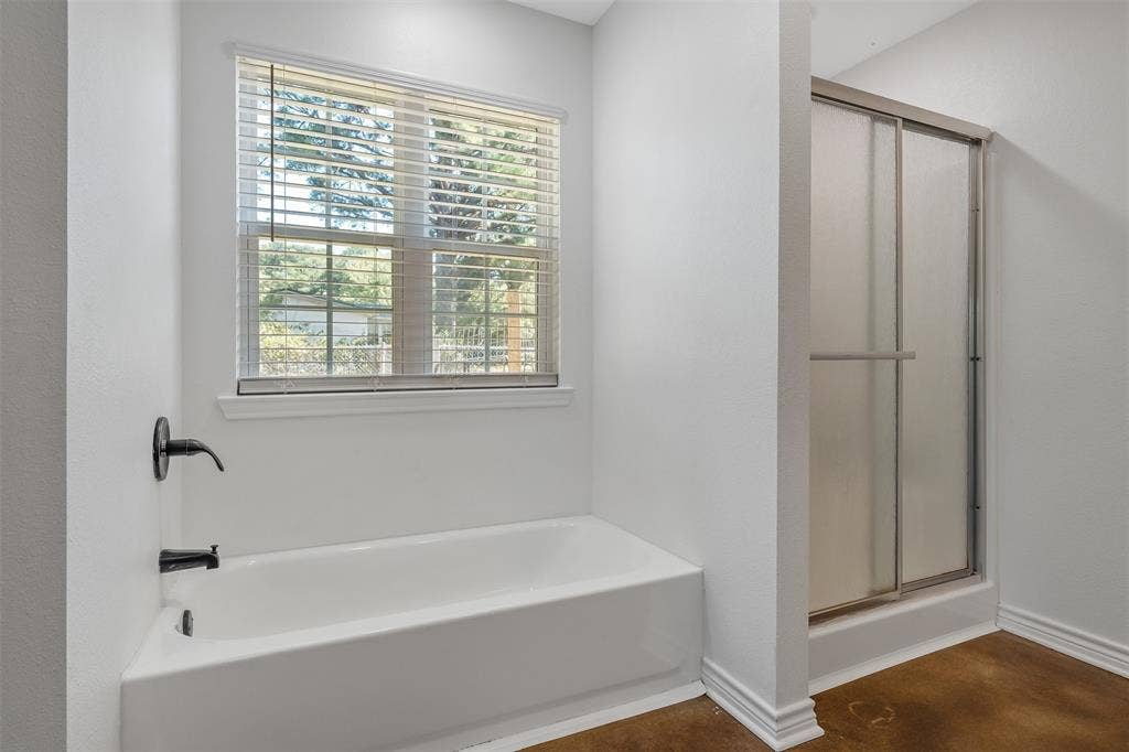 19731 County Road 4130, Lindale, TX 75771 White tub with matte black fixtures, a window with blinds, and a shower with frosted sliding glass doors