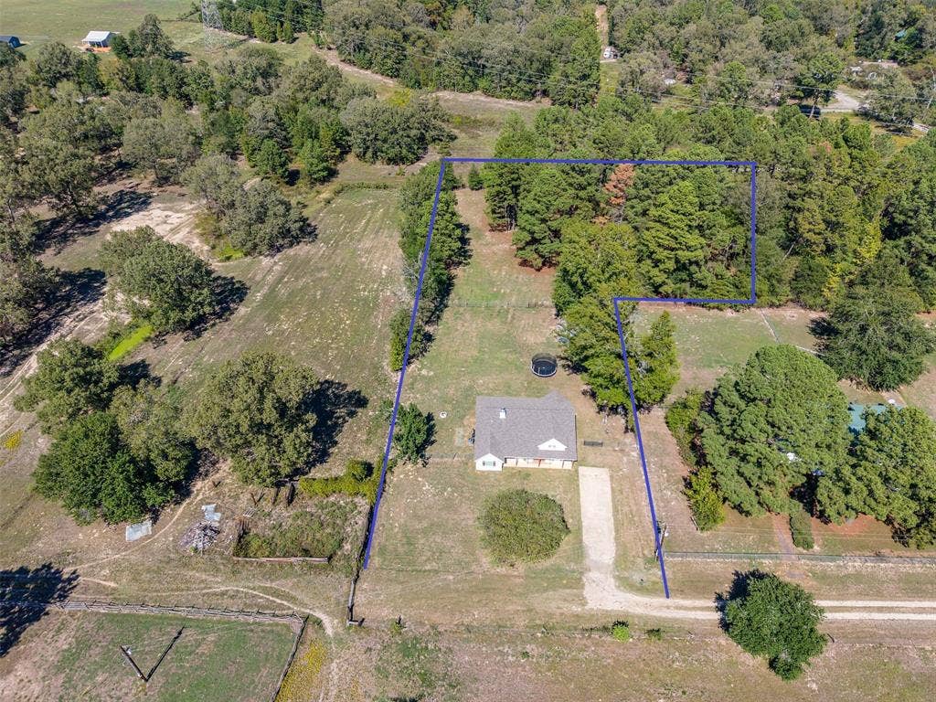 19731 County Road 4130, Lindale, TX 75771 Expansive property featuring a single-story residence with a gray shingle roof, mature trees, and a gravel driveway