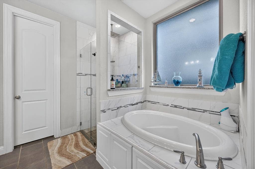 1416 White Squall Trail, Arlington, TX 76005 Soaking tub with brushed nickel fixtures, an enclosed glass shower, a tiled shower interior, and dark tile flooring