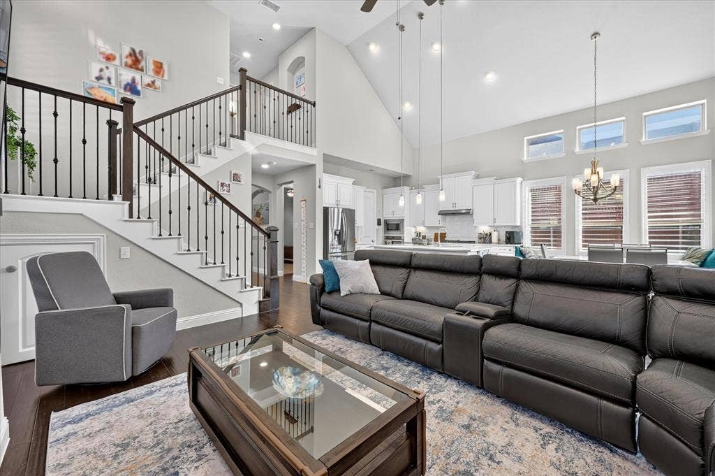 1416 White Squall Trail, Arlington, TX 76005 Open concept floor plan featuring vaulted ceilings, wood-finish flooring, a two-story staircase with iron balusters, and a kitchen with white cabinetry