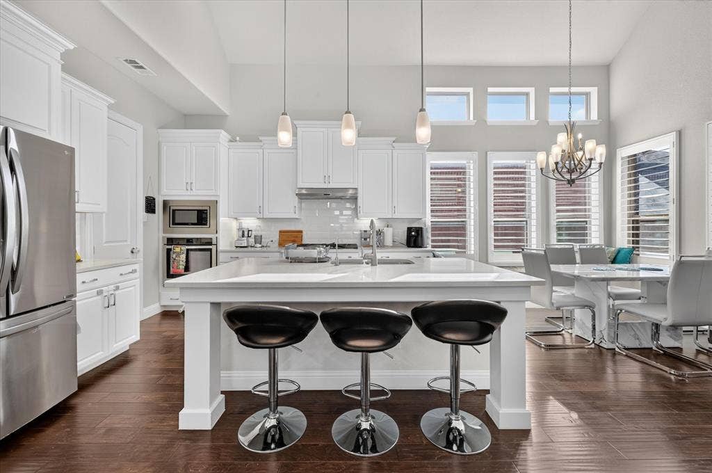 1416 White Squall Trail, Arlington, TX 76005 Spacious kitchen featuring white cabinetry, stainless steel appliances, a large center island, and wood-finish flooring