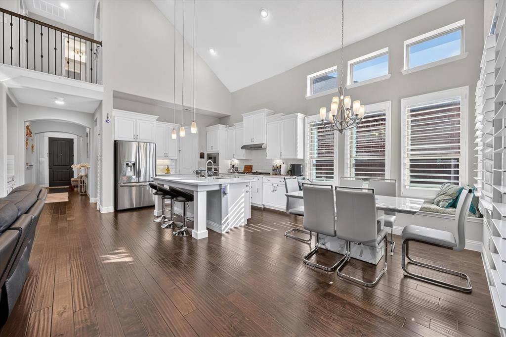 1416 White Squall Trail, Arlington, TX 76005 Vaulted ceiling, wood-finish flooring, white cabinetry, stainless steel appliances, and a kitchen island with pendant lighting