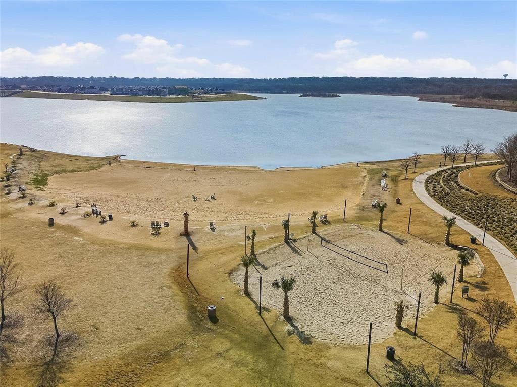 1416 White Squall Trail, Arlington, TX 76005 Lakefront property featuring a sandy beach area, dedicated sand volleyball court, established palm trees, and an extensive paved pathway