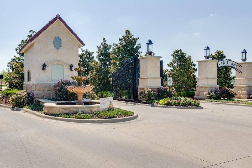 1416 White Squall Trail, Arlington, TX 76005 Stone-clad entry columns with decorative lanterns, a tiered fountain, and a stucco guardhouse with a tiled roof