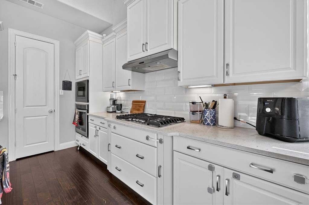 1416 White Squall Trail, Arlington, TX 76005 White shaker-style cabinetry, subway tile backsplash, gas cooktop, built-in double ovens, and wood-finish flooring