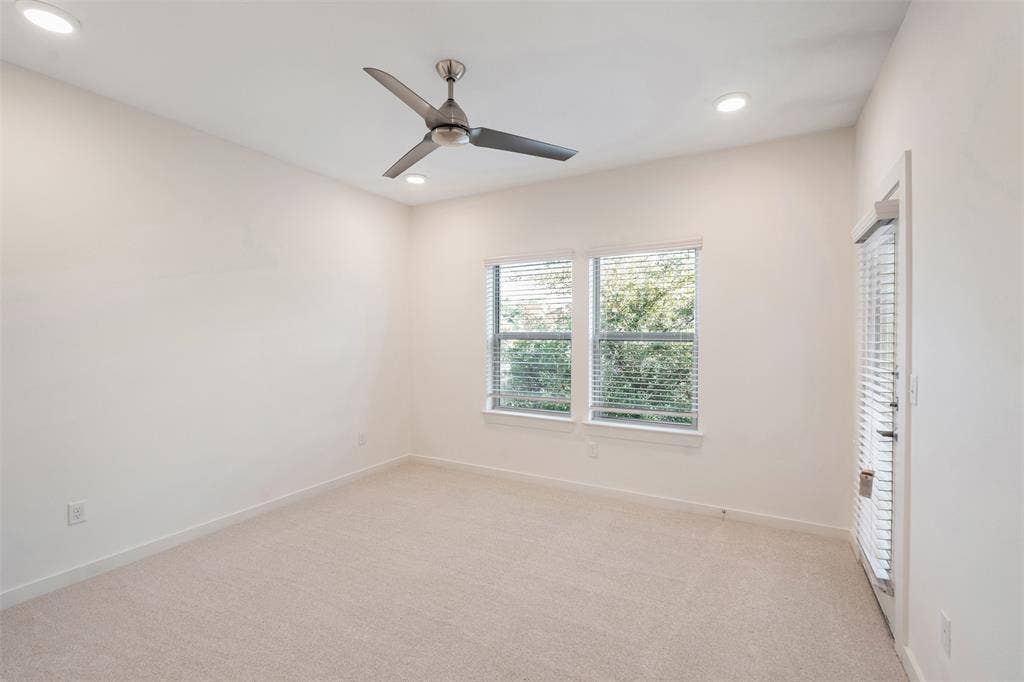 Neutral carpet flooring, recessed ceiling lighting, a ceiling fan, dual windows with blinds, and a glass-paneled door