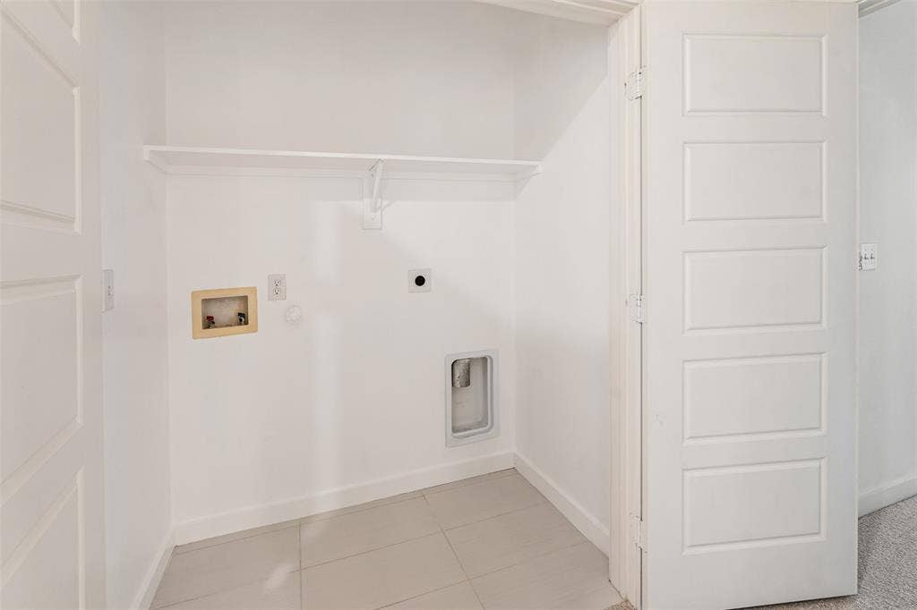 Laundry area featuring tile flooring, a white shelving unit, and a panel door