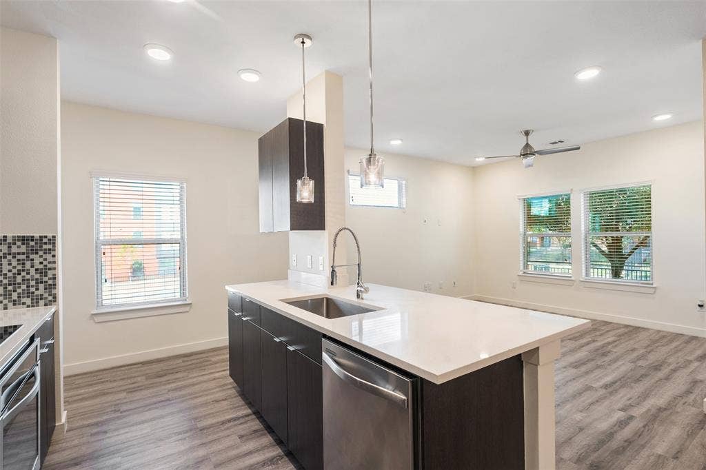 Spacious kitchen island with a single basin sink, integrated dishwasher, and pendant lighting