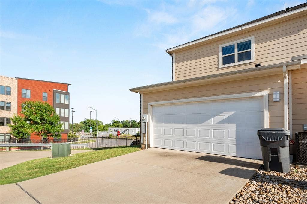 Two-car garage with panel detailing, light beige siding, and a concrete driveway