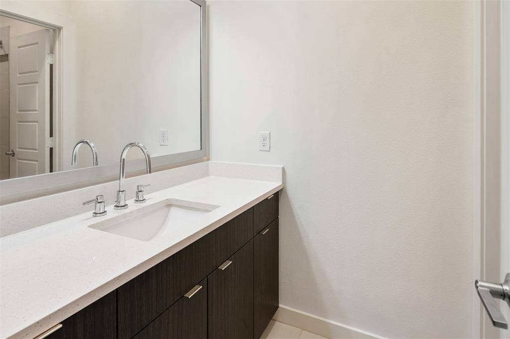 Floating vanity with dark wood-finish cabinetry, chrome hardware, and an integrated rectangular sink