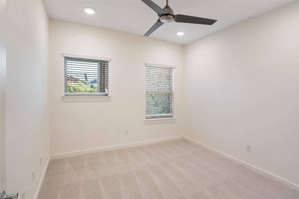 Recessed ceiling lighting, ceiling fan, two windows with blinds, and light-toned carpeting