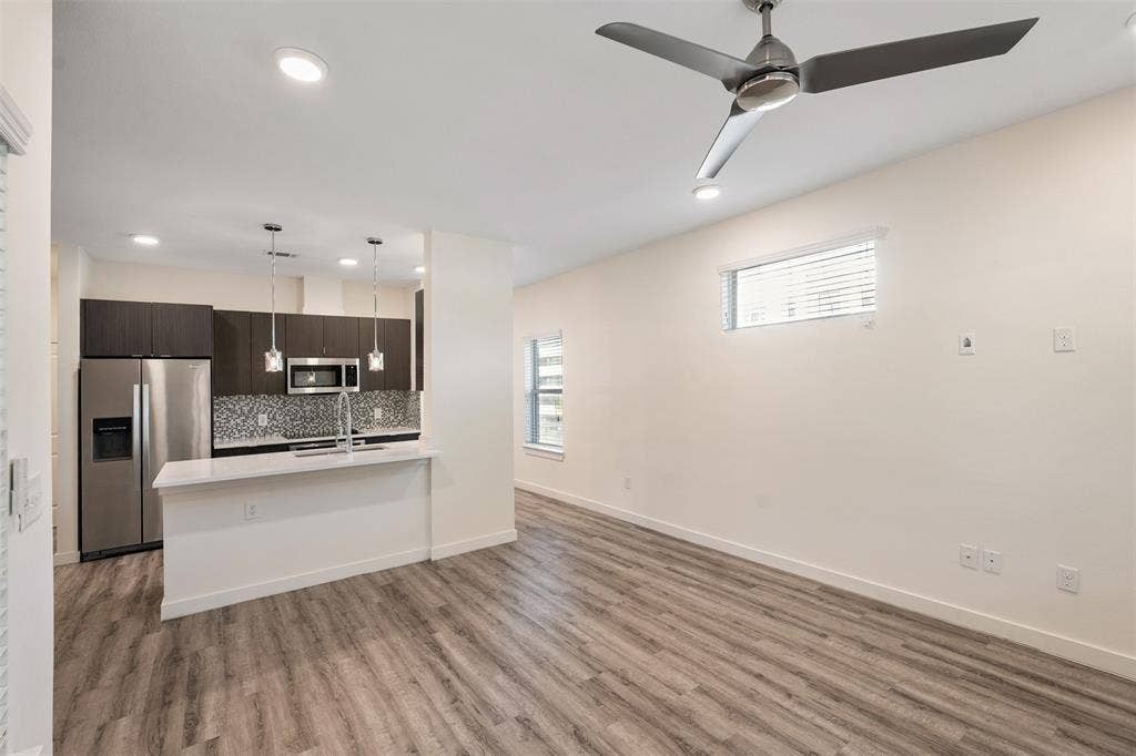 Integrated kitchen with stainless steel appliances, mosaic tile backsplash, and white countertop