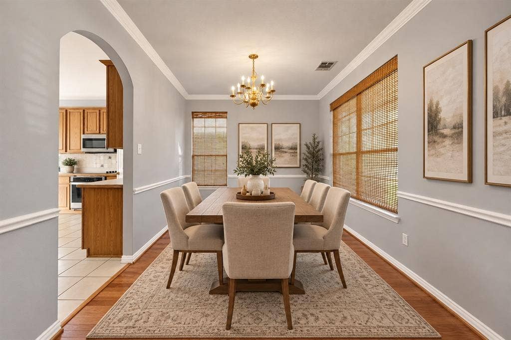 Hardwood-style flooring throughout, crown molding, chair rail detailing, recessed ceiling, and an arched entryway