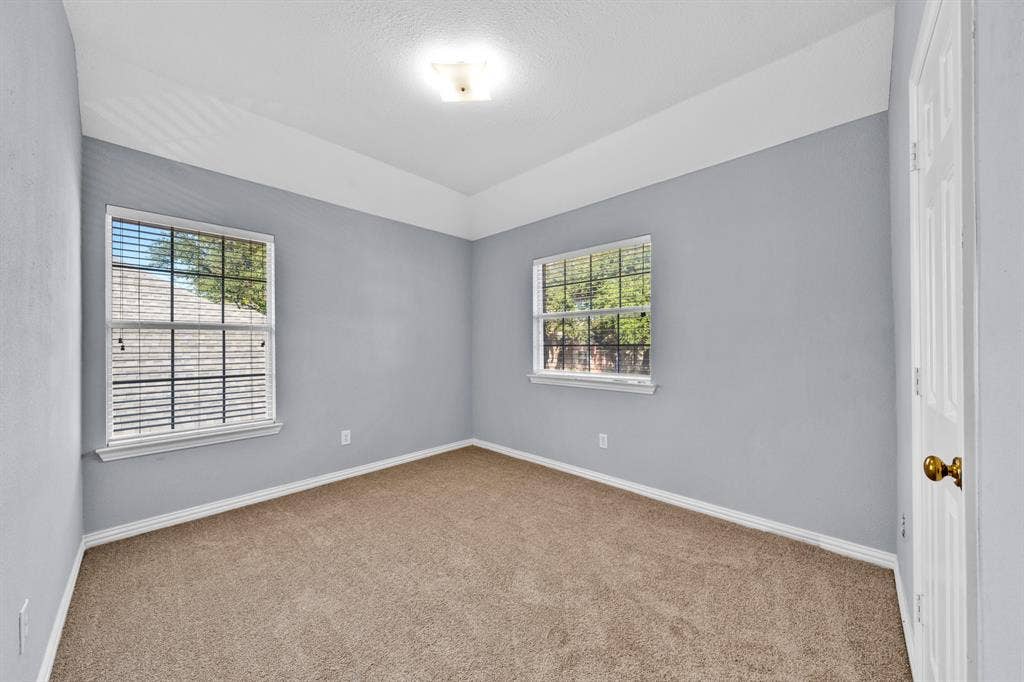Carpeted flooring, two windows with blinds, light blue walls, white trim, and a ceiling-mounted light fixture