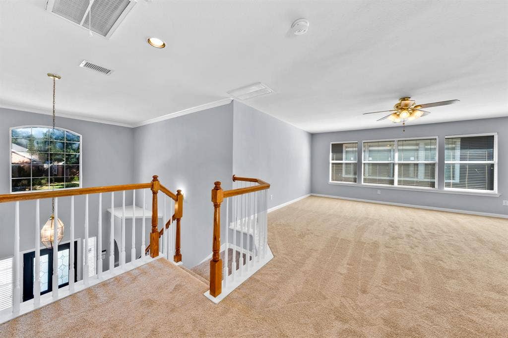 Carpeted upper level featuring a wood and white spindle railing, arched window, recessed lighting, and a ceiling fan with light fixture