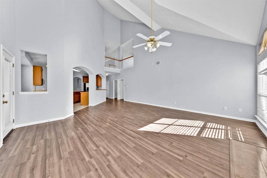 Vaulted ceilings, wood-finish flooring, architectural archways, and an upper-level railing