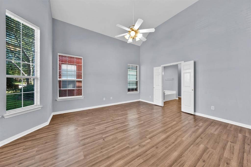 Wood-finish flooring, vaulted ceiling, ceiling fan, multiple windows, and double doors