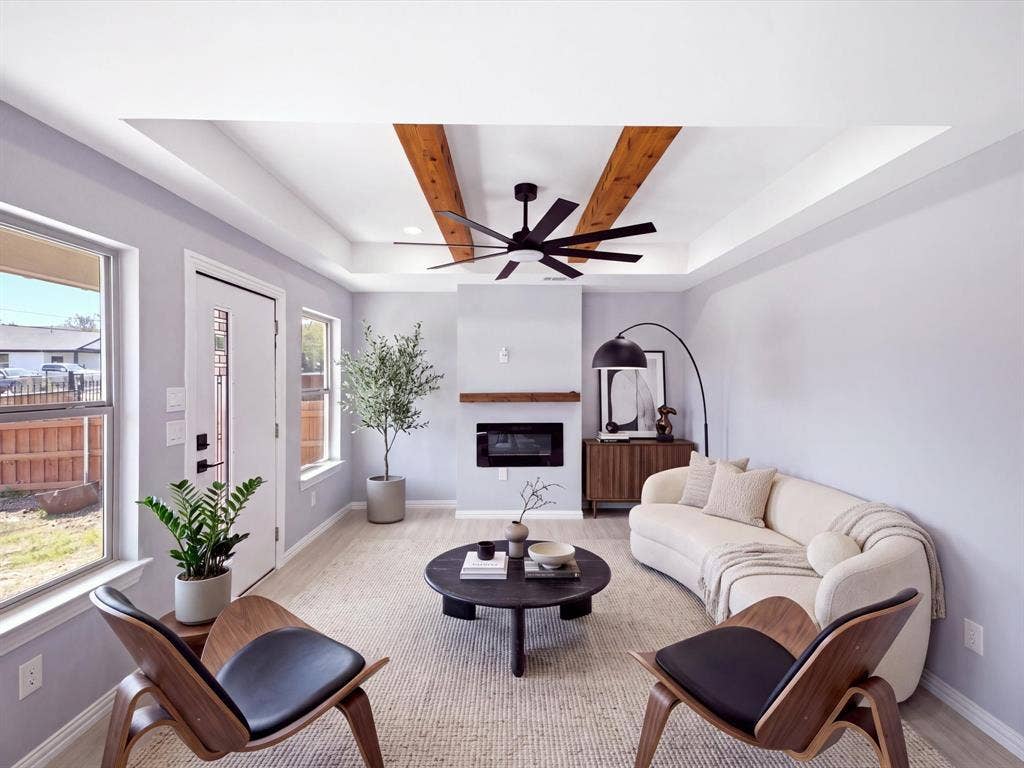 1727 Mentor Avenue, Dallas, TX 75216 Tray ceiling with wood beam accents, ceiling fan, contemporary fireplace with wood mantel, wood-finish flooring, and white trim
