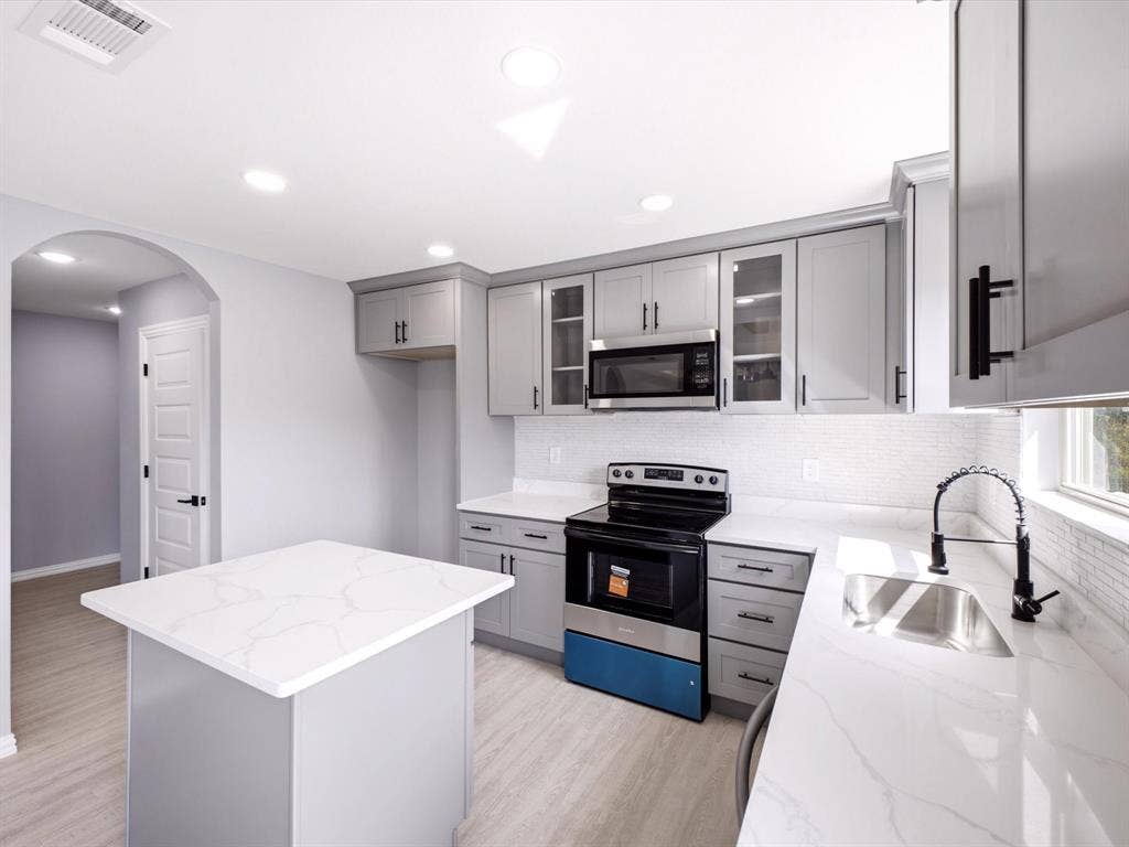 1727 Mentor Avenue, Dallas, TX 75216 Kitchen featuring light gray cabinetry, white countertops, tile backsplash, stainless steel sink with a matte black faucet, and wood-finish flooring