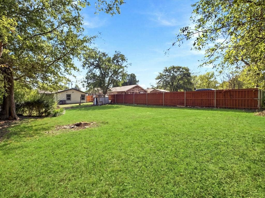 1727 Mentor Avenue, Dallas, TX 75216 Expansive backyard featuring a manicured lawn, mature trees, and a privacy fence