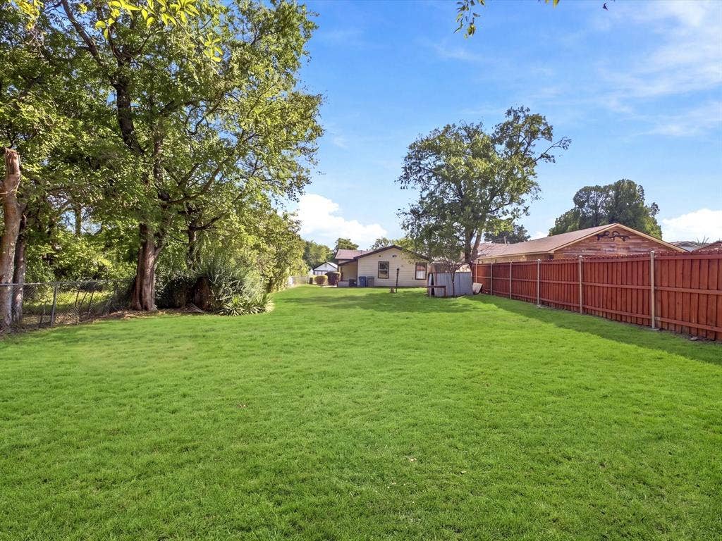 1727 Mentor Avenue, Dallas, TX 75216 Expansive green lawn with mature trees and a wood privacy fence