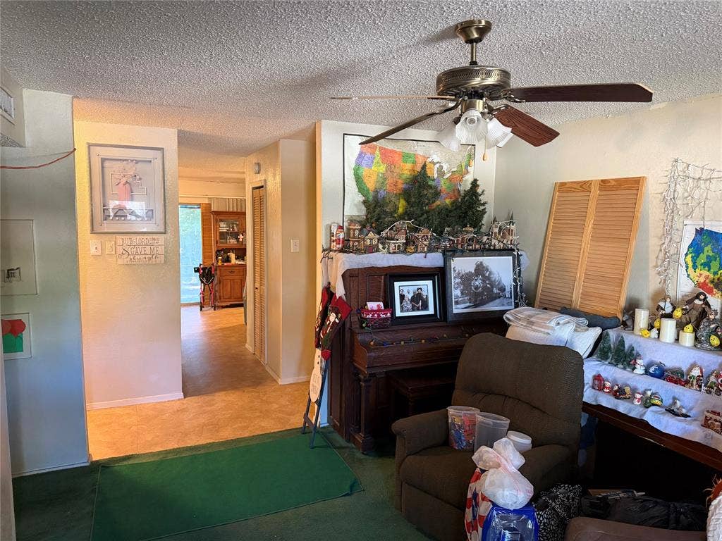 4031 Hartford Drive, Garland, TX 75043 Textured ceiling with a ceiling fan featuring a brass-tone base and wood-finish blades