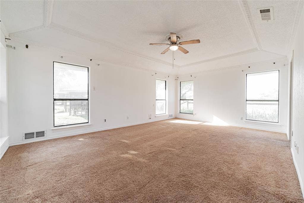 4320 Hickox Road, Rowlett, TX 75089 Spacious room featuring tray ceilings, neutral carpeting, a ceiling fan with integrated lighting, and multiple windows