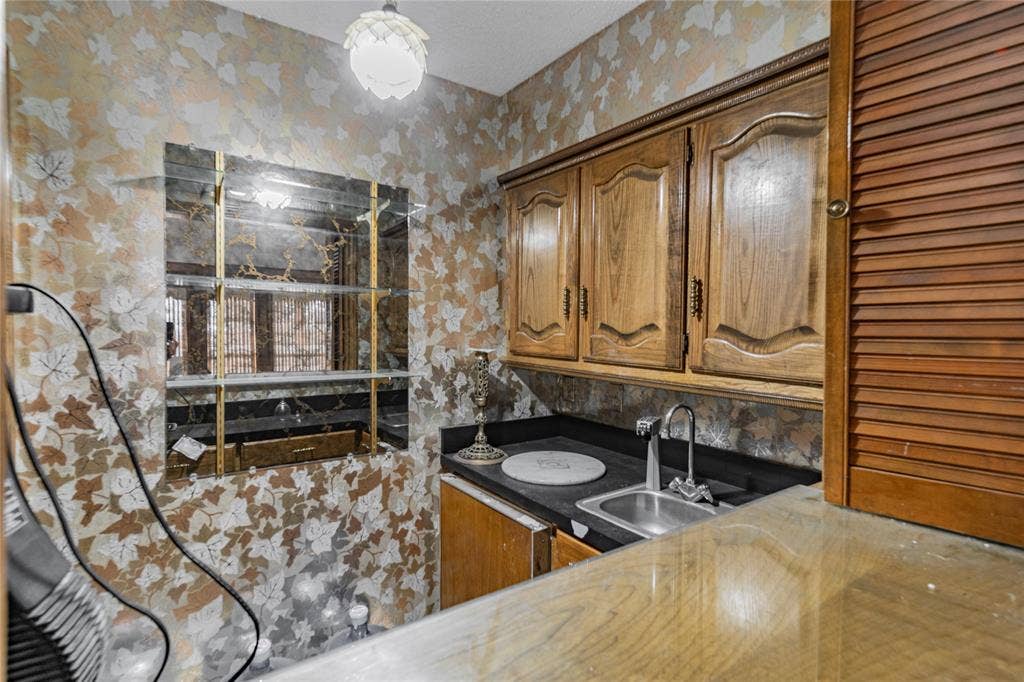 4320 Hickox Road, Rowlett, TX 75089 Built-in wet bar featuring wood cabinetry, a stainless steel sink, and dark countertops